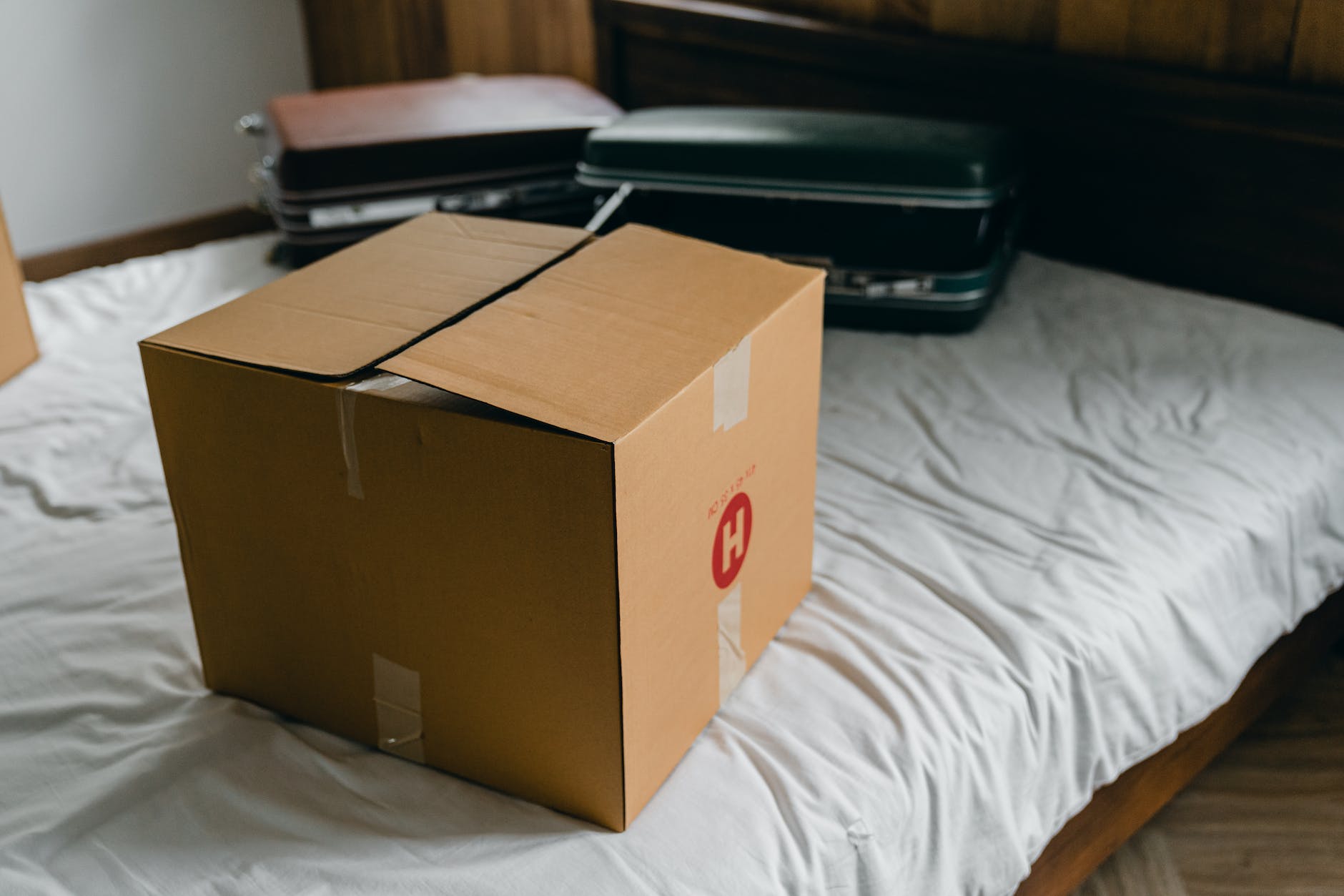 carton box and suitcases for relocation on bed